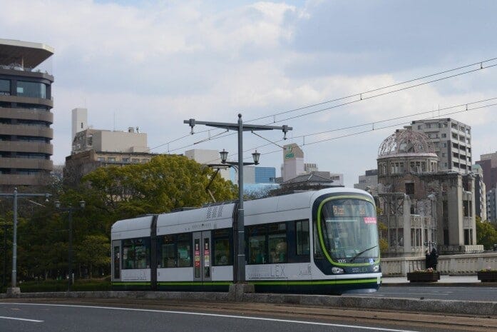 原爆ドームをバックに快走する超低床式車両Green mover LEX