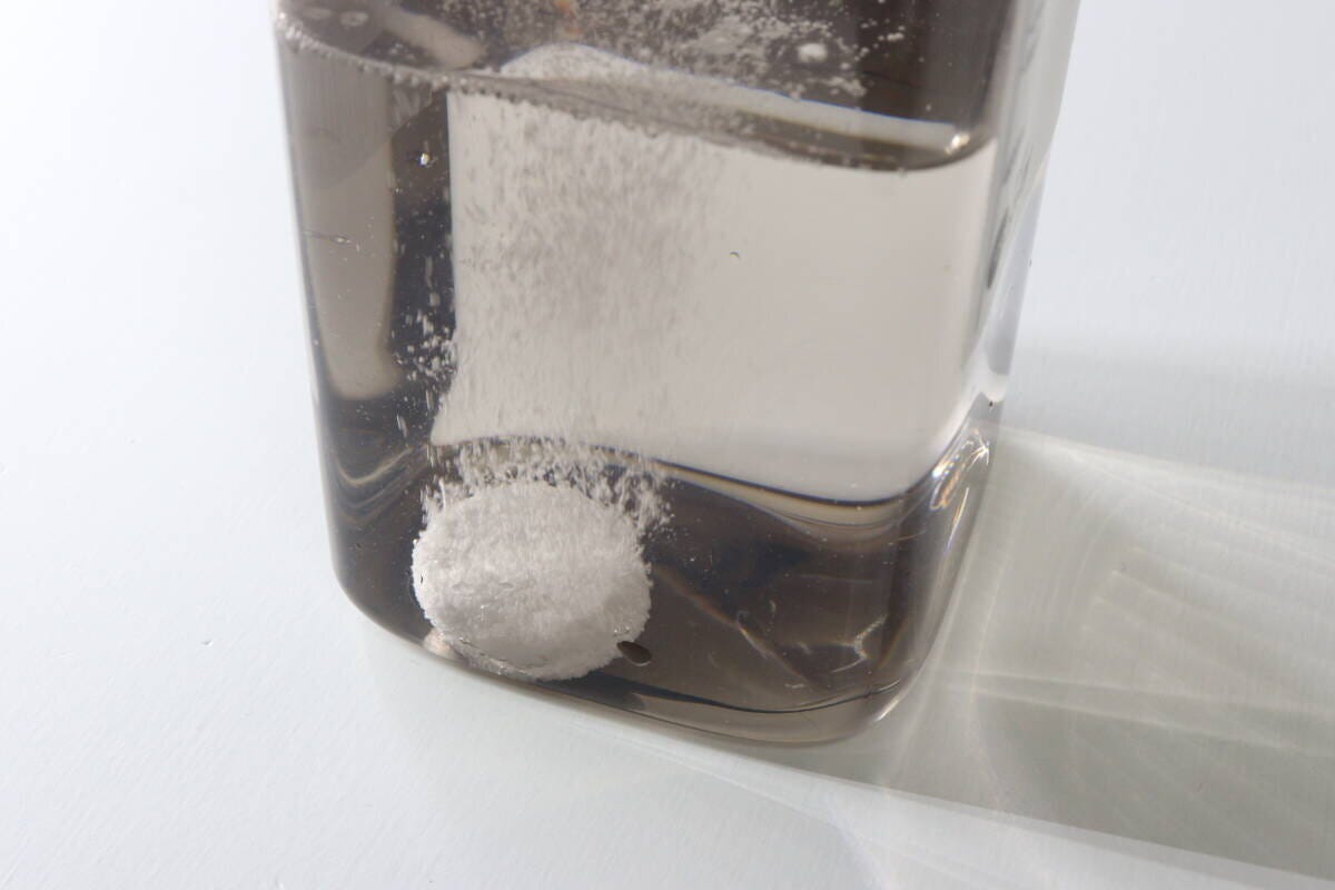 茶色い容器の水の中で錠剤が発泡しながら溶けていく瞬間 茶色い容器の水の中で錠剤が発泡しながら溶けていく瞬間