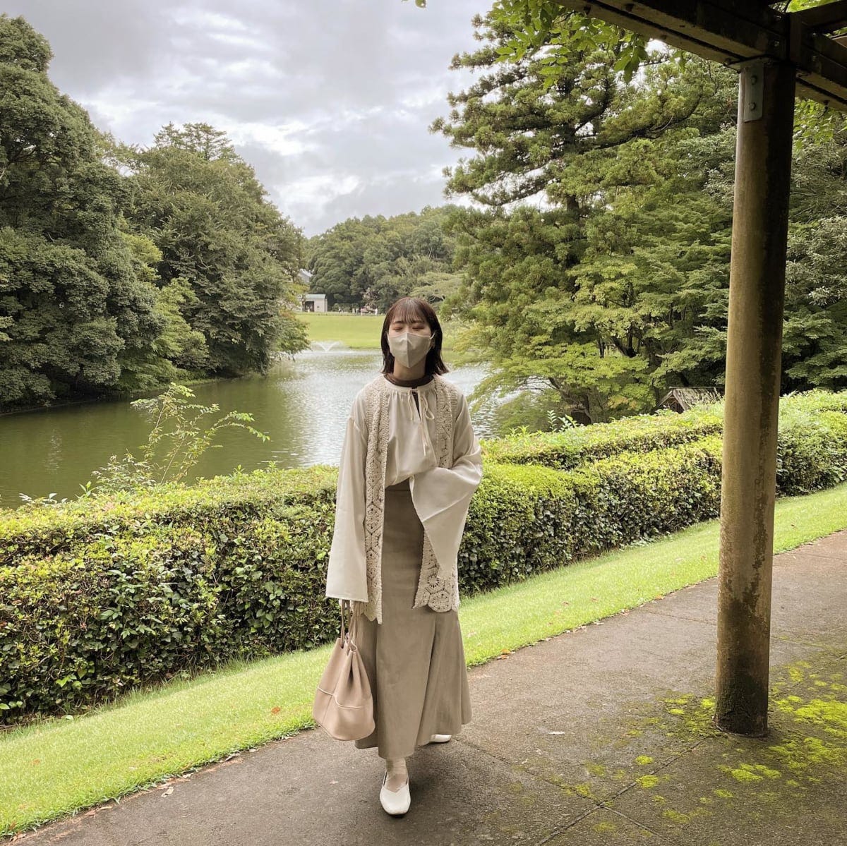 スカートとブラウスにレースカーデを合わせた淡色コーデの女性