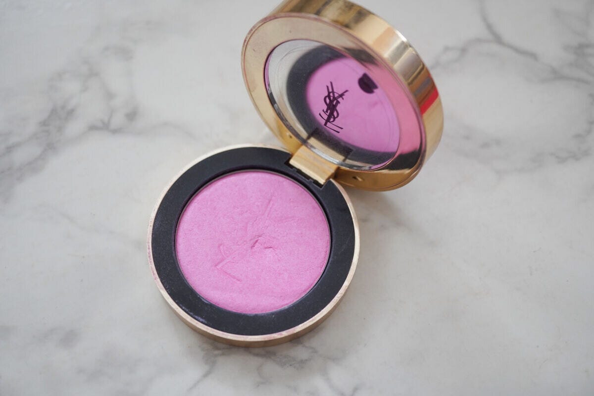 イヴ・サンローラン・ボーテのゴールドコンパクトに入ったペールピンクのパウダーチークを大理石の上に置いた商品俯瞰