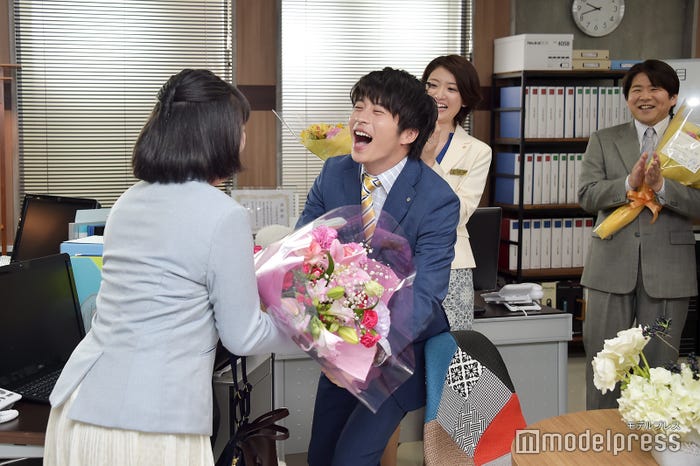 まいまい(伊藤修子)の笑い方を真似しながら近づき、花束を手渡す田中圭。(C)モデルプレス