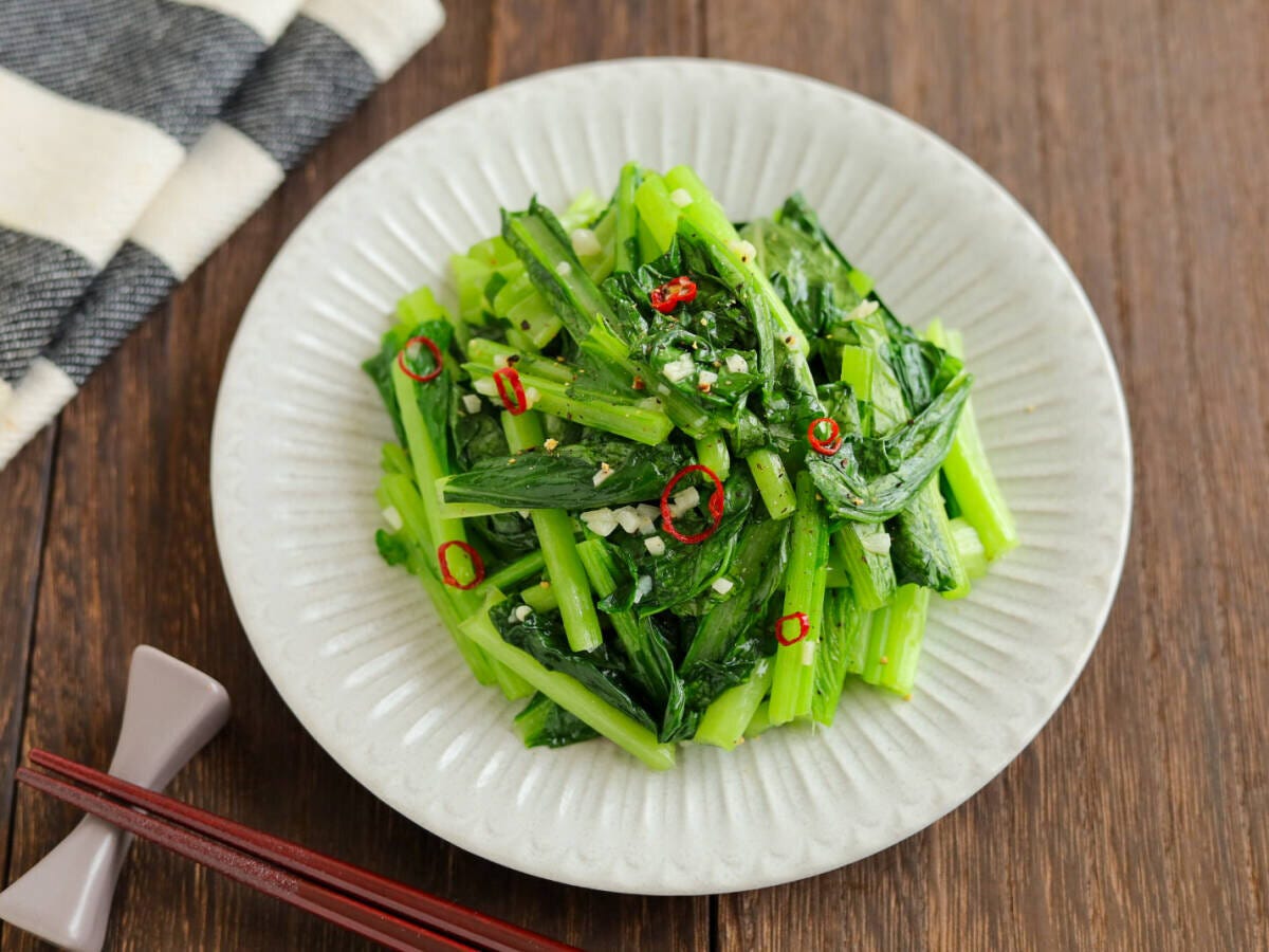 白い皿に盛り付けられた小松菜のペペロンチーノ風炒めと箸の俯瞰 白い皿に盛り付けられた小松菜のペペロンチーノ風炒めと箸の俯瞰