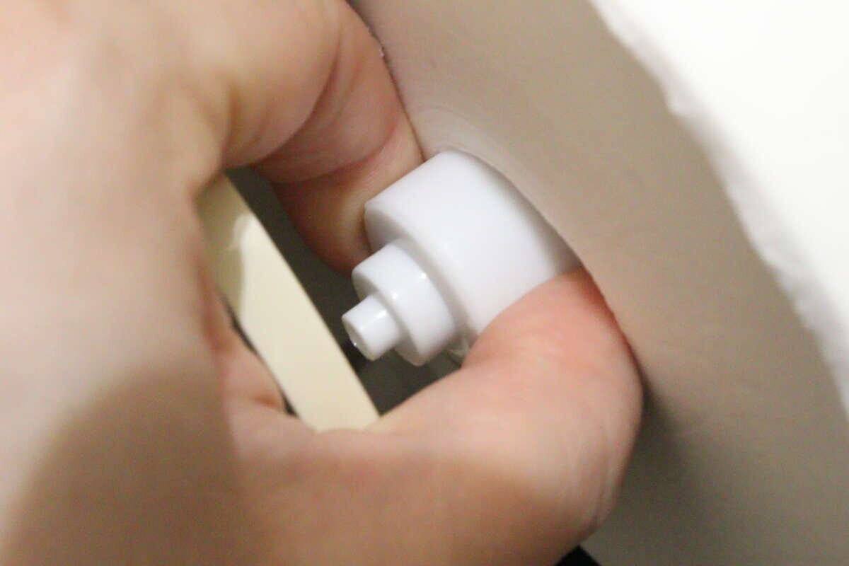 女性の手が新しい替え芯ホルダーをトイレットペーパーホルダーに差し込んでいる 女性の手が新しい替え芯ホルダーをトイレットペーパーホルダーに差し込んでいる