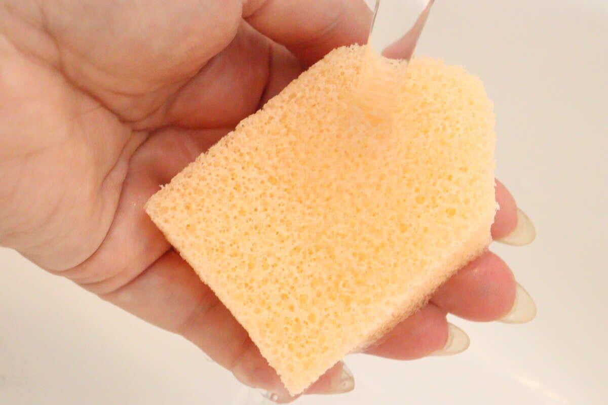 手に持ったハウス型洗顔パフに蛇口から水をかけている 手に持ったハウス型洗顔パフに蛇口から水をかけている