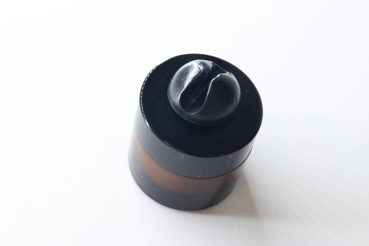 黒いコスメジャーの蓋に貼り付けられたスパチュラホールド