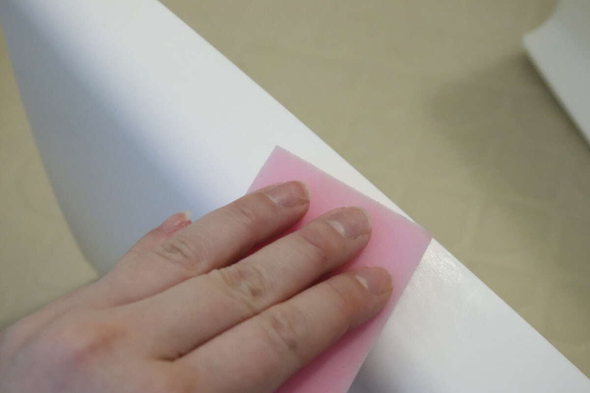 ピンクのメラミンスポンジでお風呂の椅子を掃除する手