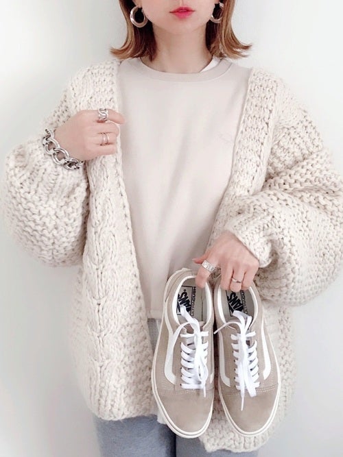 白のざっくりカーディガンを着た女性がVANSスニーカーを持っている画像