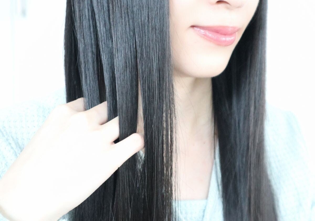 手で髪表面をなでてつやのあるストレートヘアに整える様子