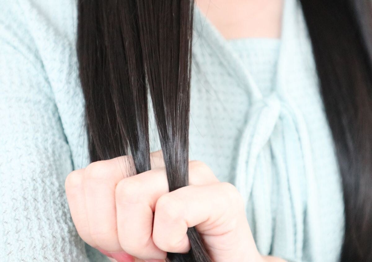 毛先を手に取りヘアオイルをなじませる女性