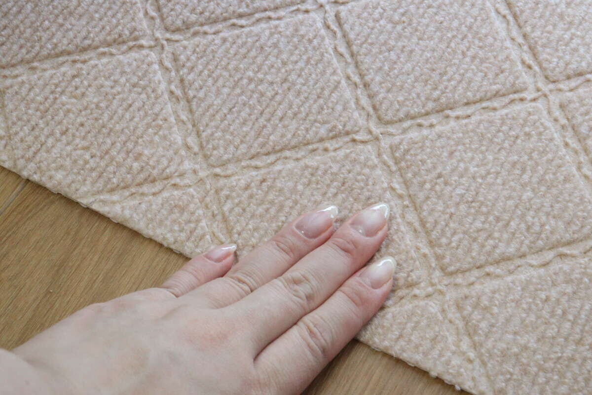 女性の手が吸着マットの表面を触って感触を確かめているクローズアップ