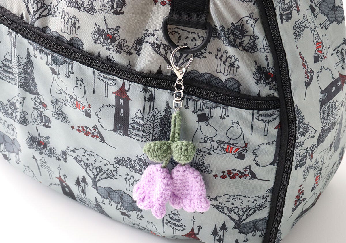 ボストンバッグのDカンに紫色の花のキーホルダーが付いている様子 ボストンバッグのDカンに紫色の花のキーホルダーが付いている様子
