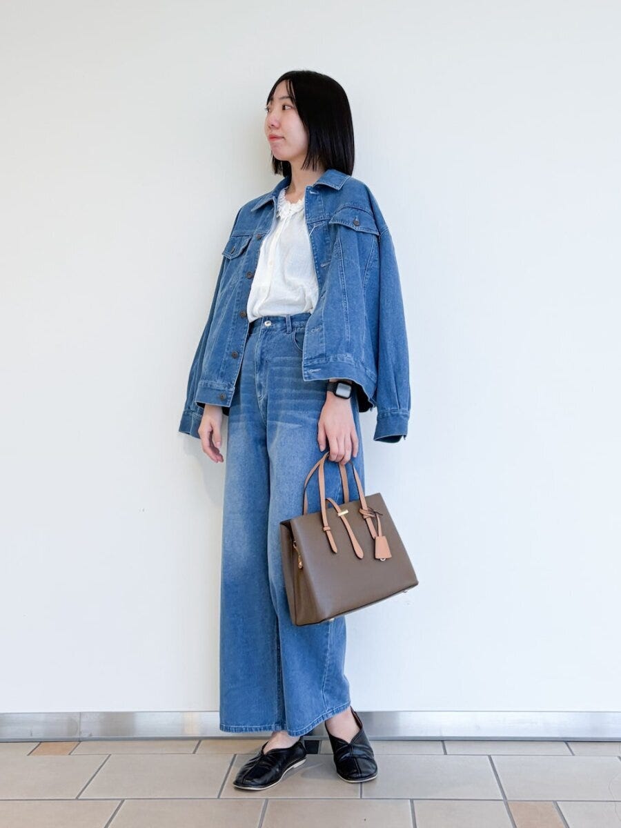 デニムジャケットとワイドパンツ、白ブラウスの女性