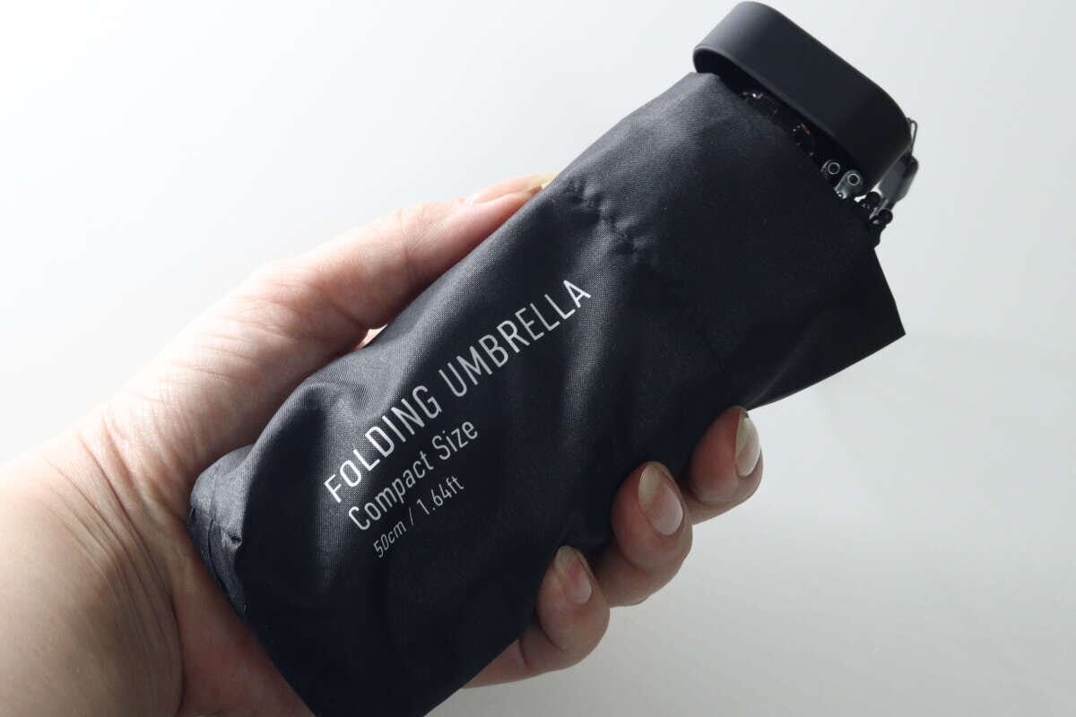 黒い折りたたみ傘が手のひらにすっぽり収まっており、コンパクトさがわかる