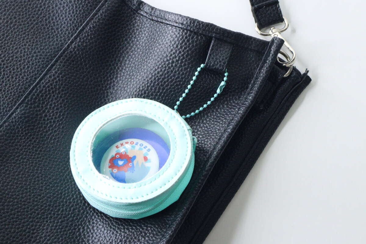 黒いバッグに水色の缶バッジケースが取り付けられている
