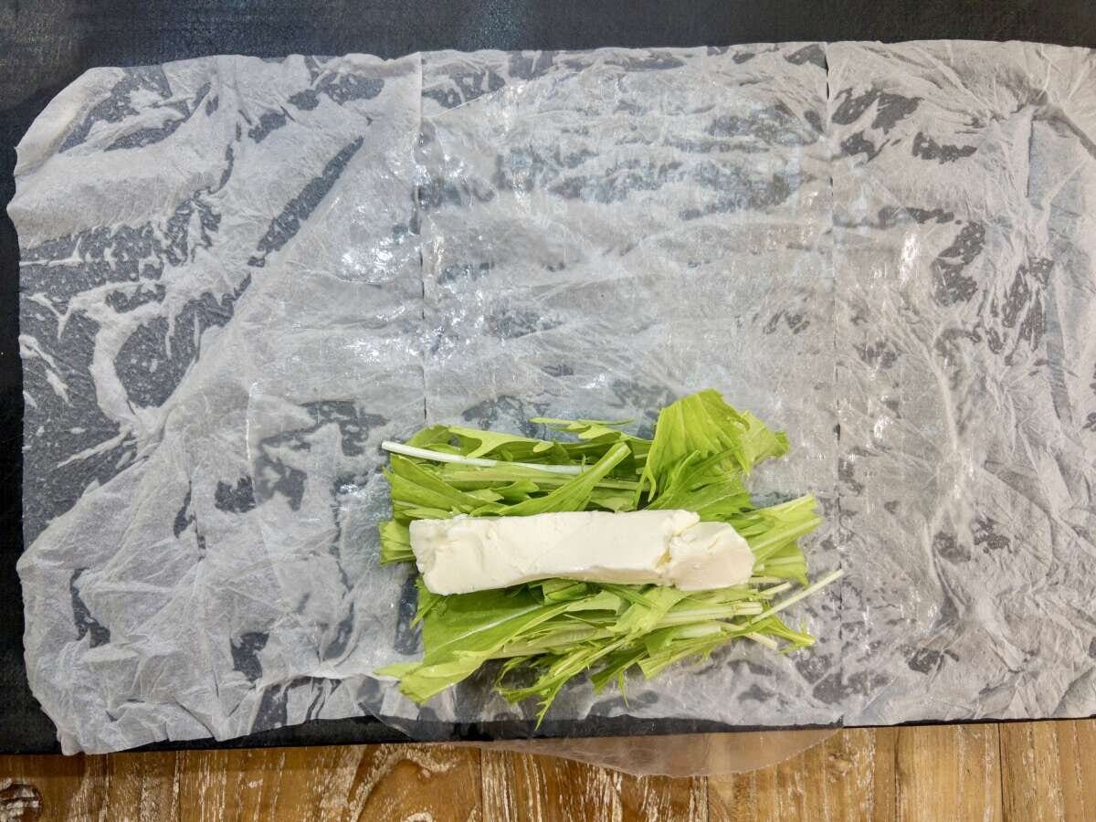 生春巻きの皮の中心にカットした水菜と棒状のクリームチーズが乗っている俯瞰写真