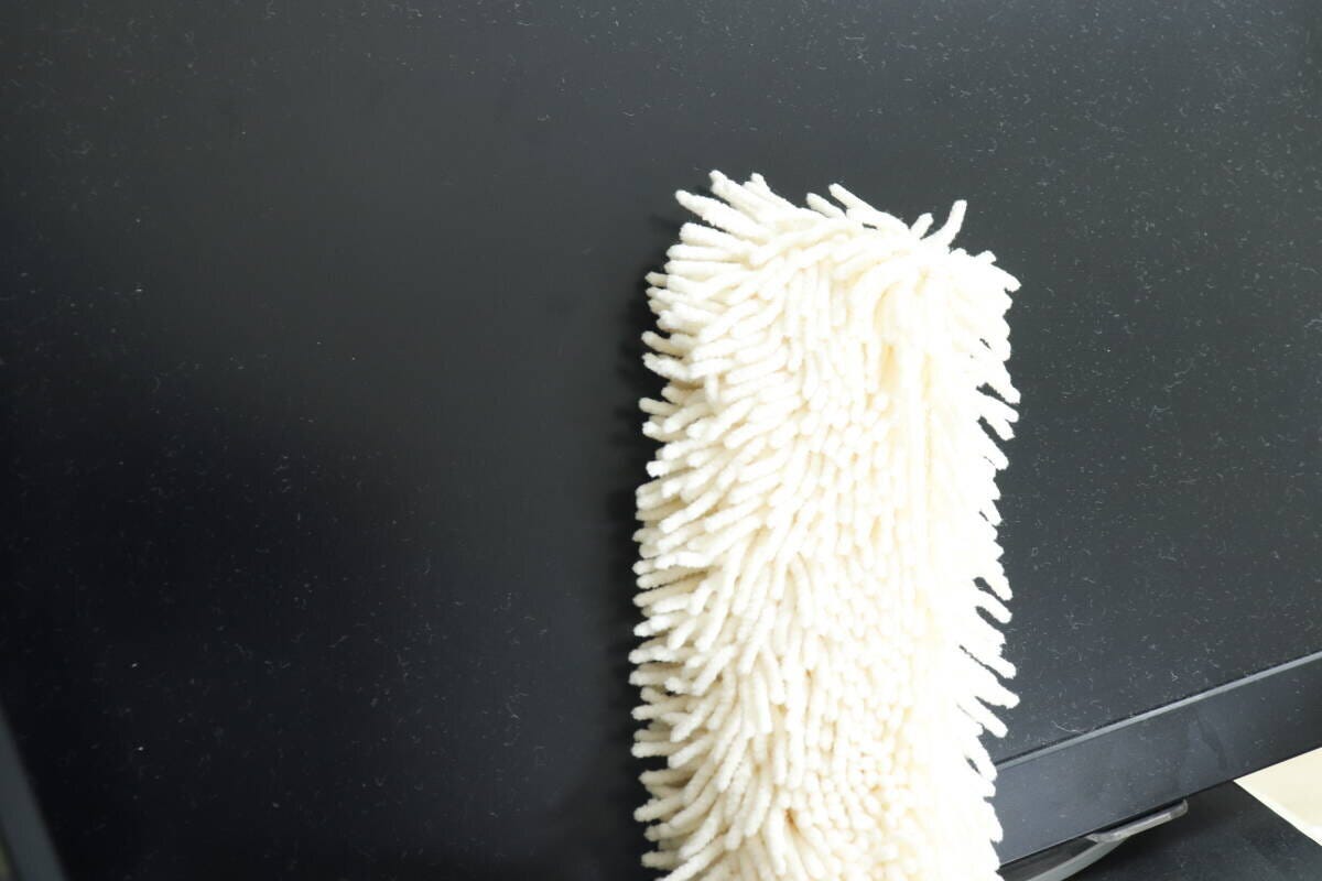 黒いモニター画面のホコリを白いハンディモップで拭いている様子 黒いモニター画面のホコリを白いハンディモップで拭いている様子