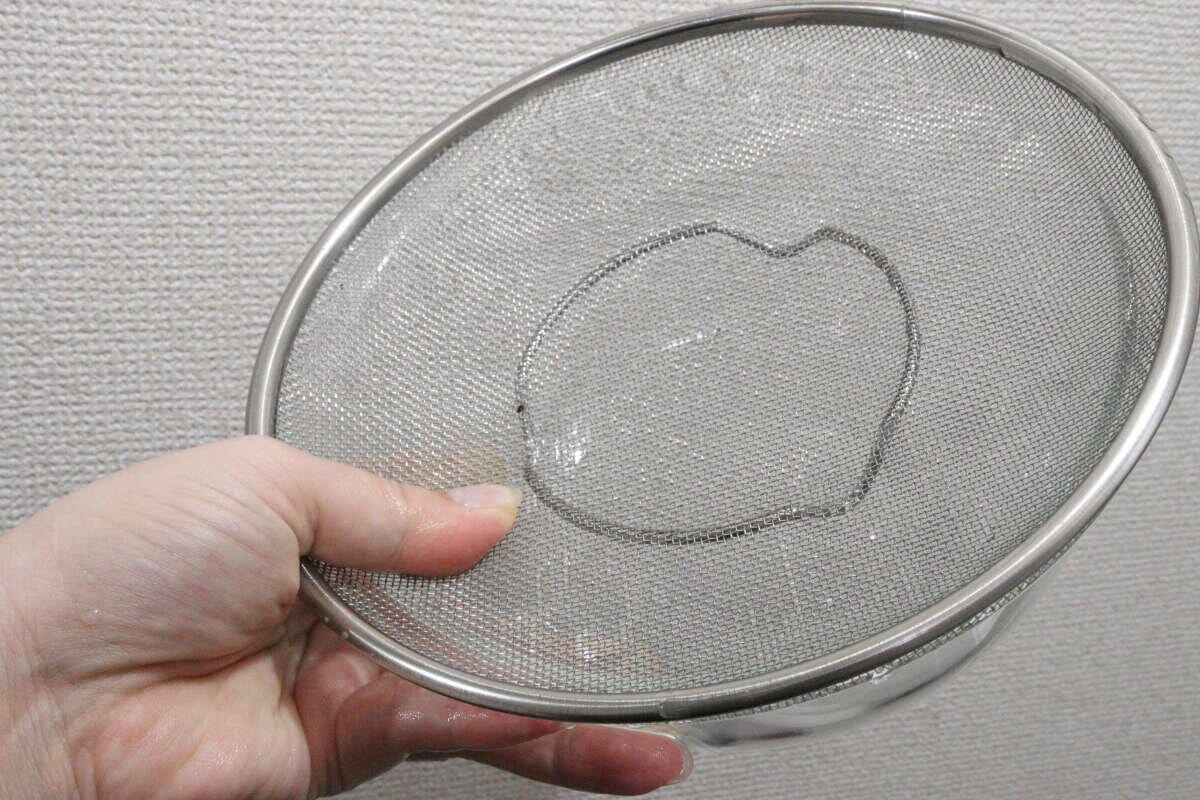 左手で浅型ザルを持ち、水が流れ落ちる様子