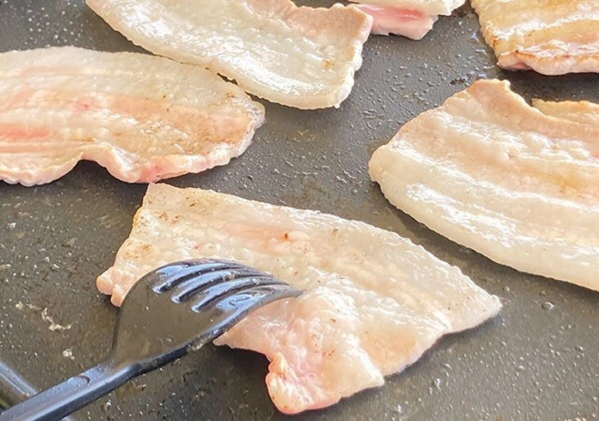 ホットプレートで焼かれている豚バラ肉を、黒いPPS樹脂製フォークでひっくり返している ホットプレートで焼かれている豚バラ肉を、黒いPPS樹脂製フォークでひっくり返している
