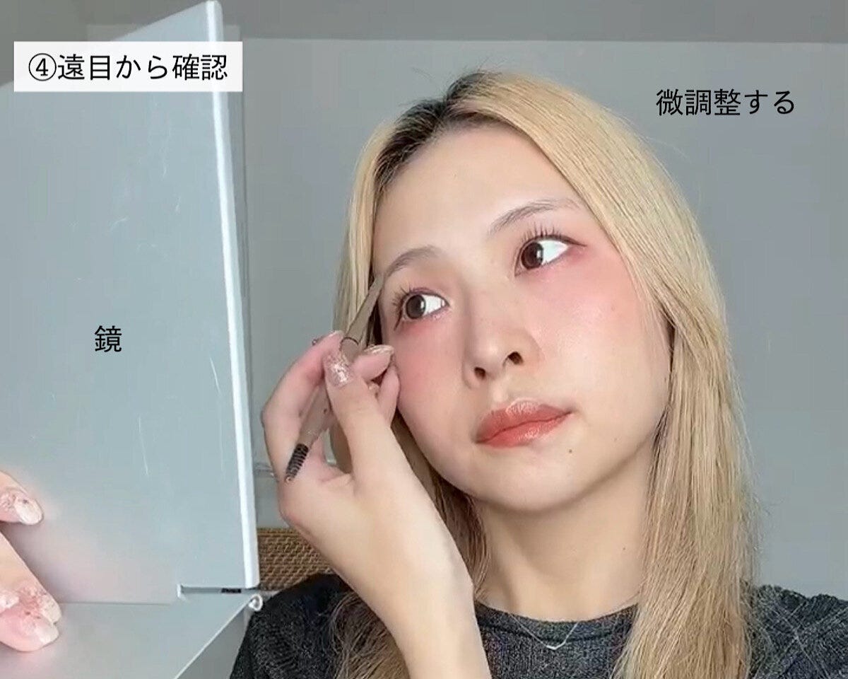 鏡で眉メイクのバランスを確認し微調整する女性 鏡で眉メイクのバランスを確認し微調整する女性