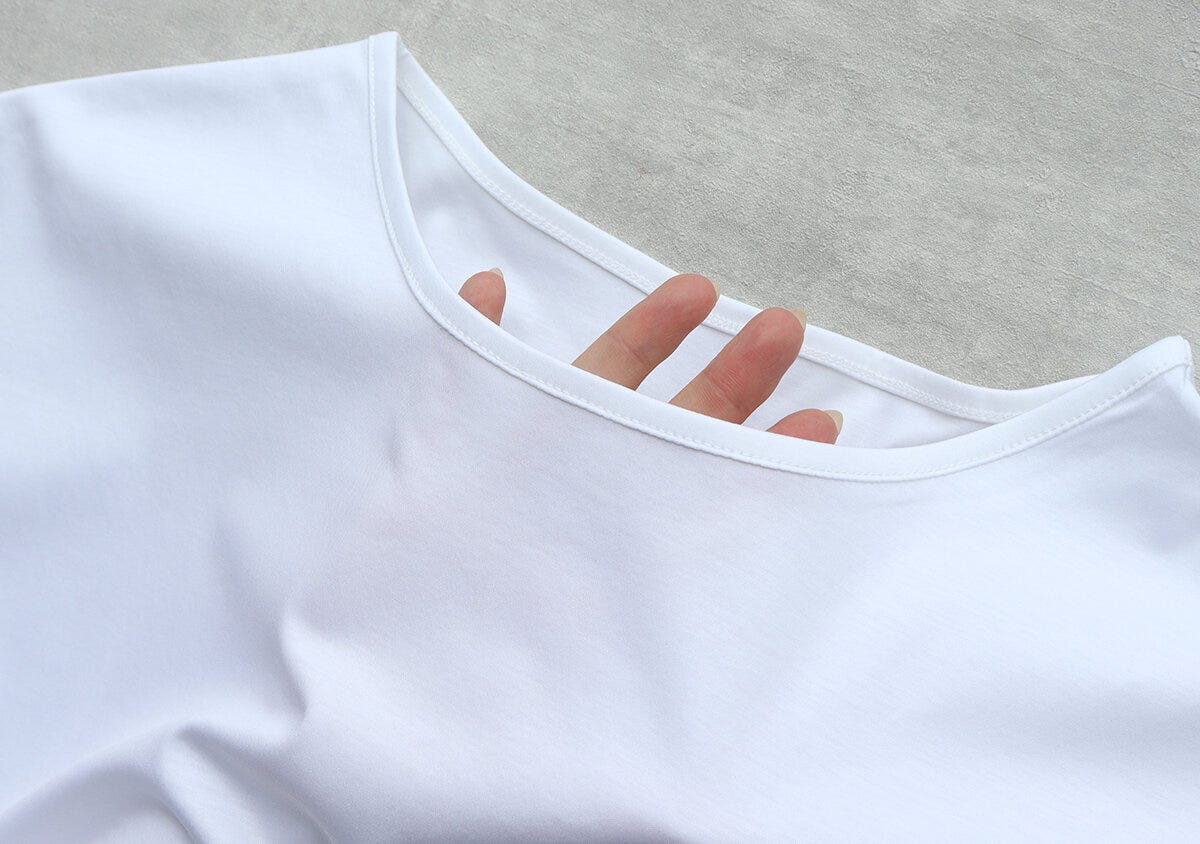 白いTシャツのボートネック部分に指を入れ透け感を確認している