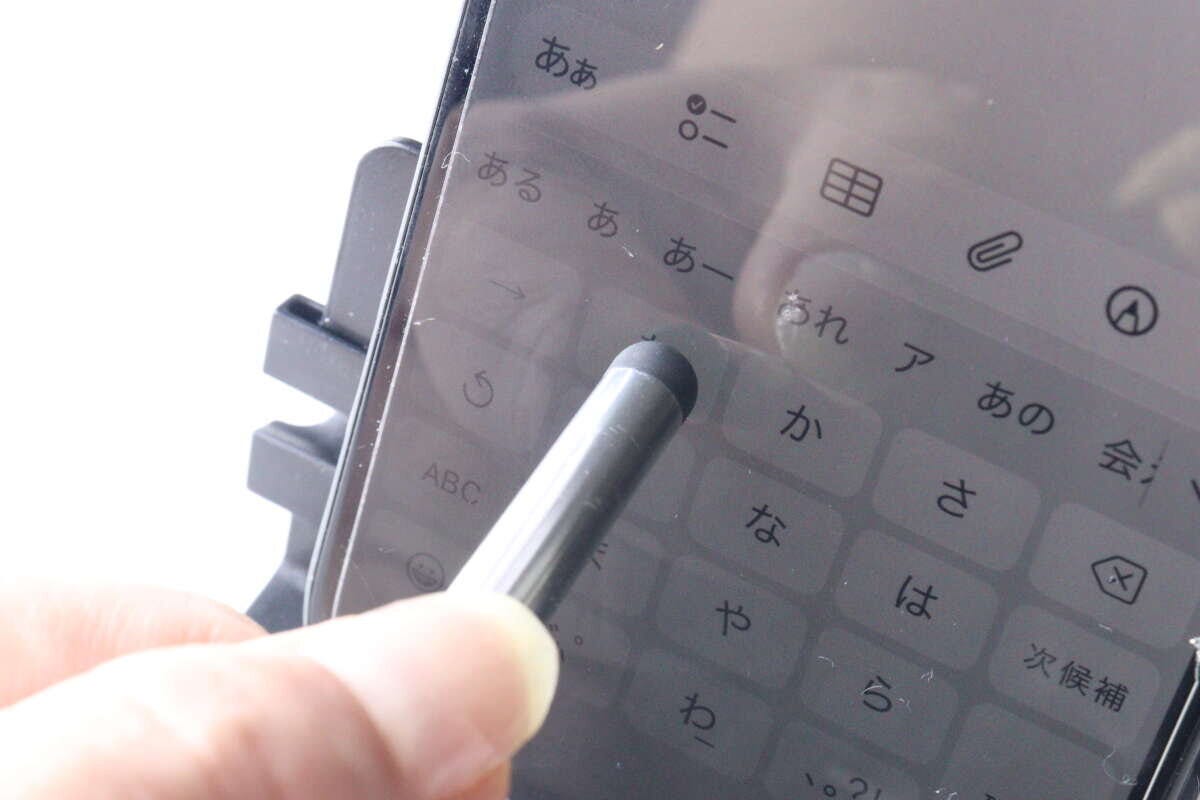 銀色のタッチペンを使って、スマートフォン画面のキーボードを操作している様子。