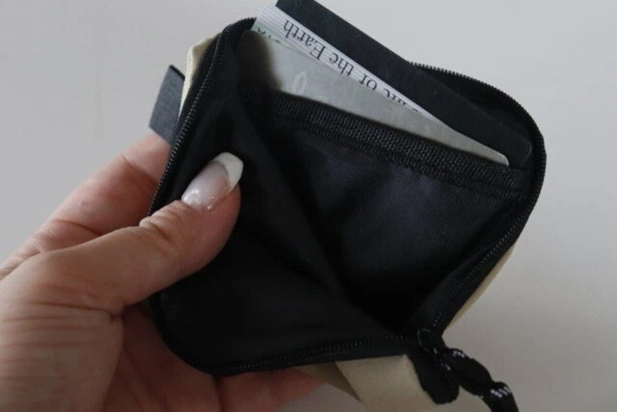 女性がベージュのコインケースのファスナーを開け、中にカードが数枚入っている 女性がベージュのコインケースのファスナーを開け、中にカードが数枚入っている