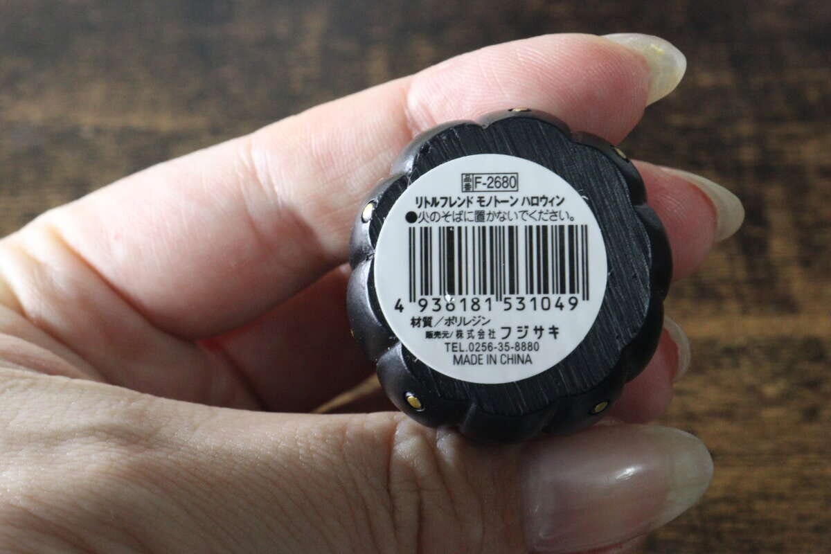 手に持った黒いかぼちゃ型オブジェの底面にある商品ラベル