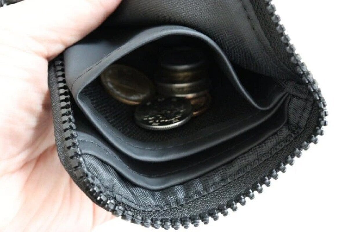 黒いL字型財布の開いた小銭入れに硬貨が見える