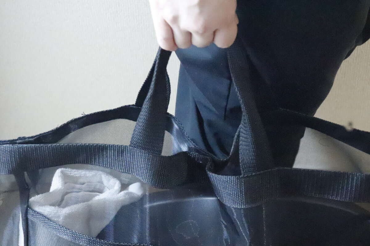 女性が黒いメッシュトートバッグの持ち手を掴んでいる 女性が黒いメッシュトートバッグの持ち手を掴んでいる