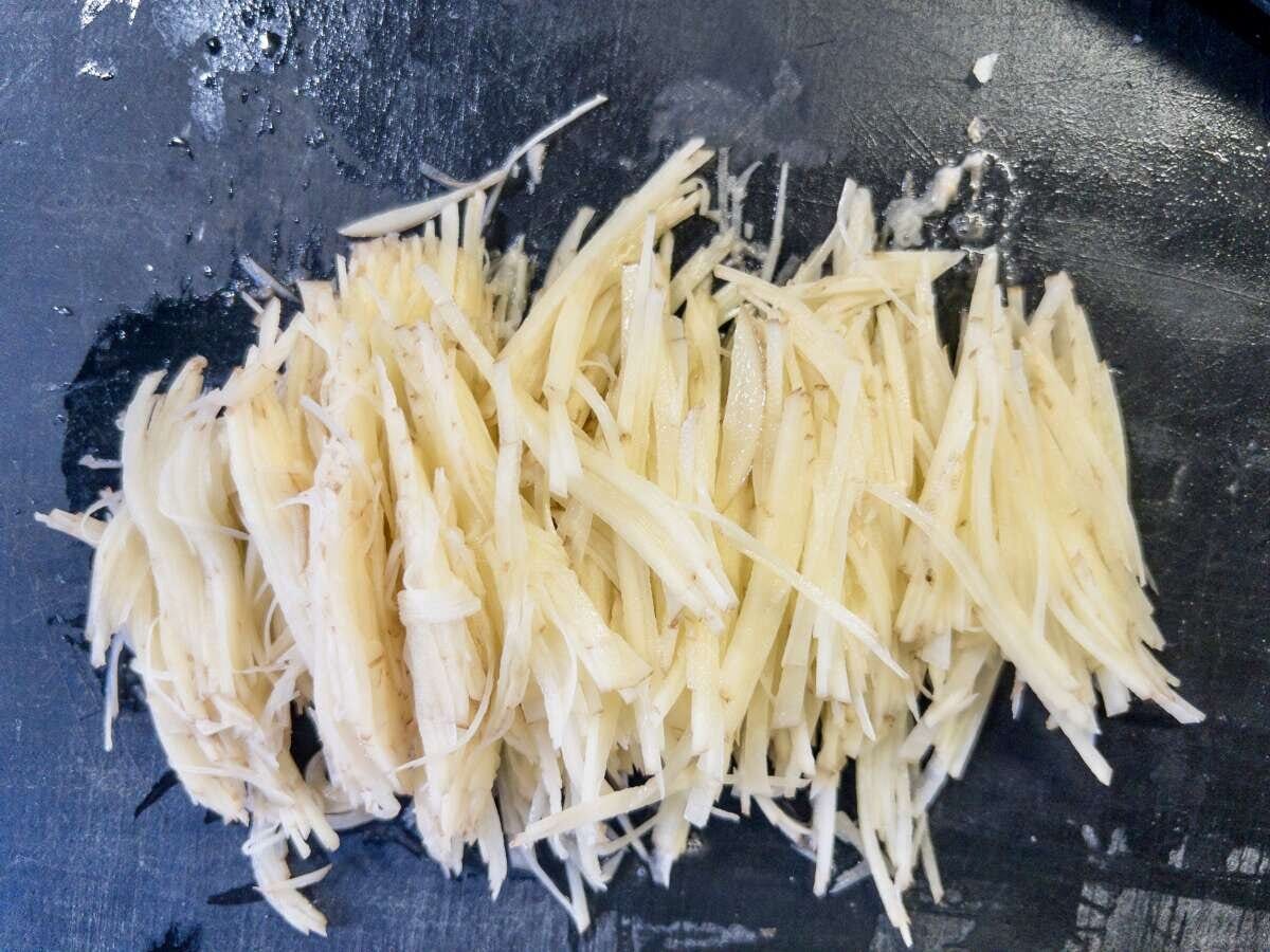 皮ごと千切りにした新じゃがいもをまな板に集めたところ