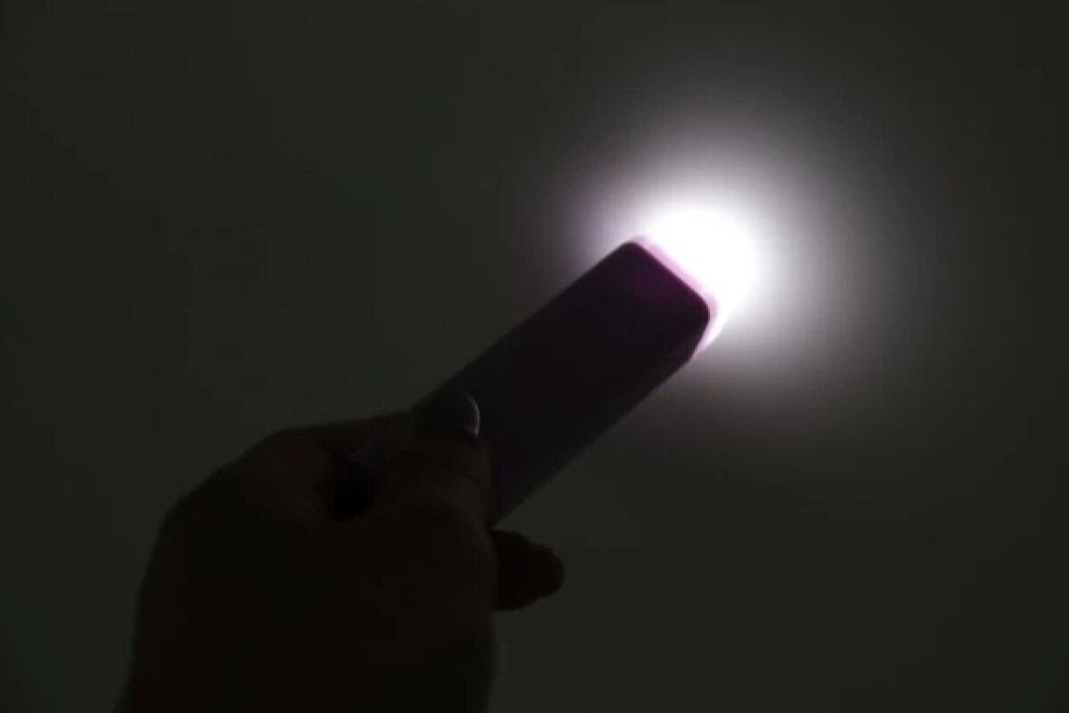 暗闇で紫色の防犯ブザーの先端から白いライトが光る様子 暗闇で紫色の防犯ブザーの先端から白いライトが光る様子
