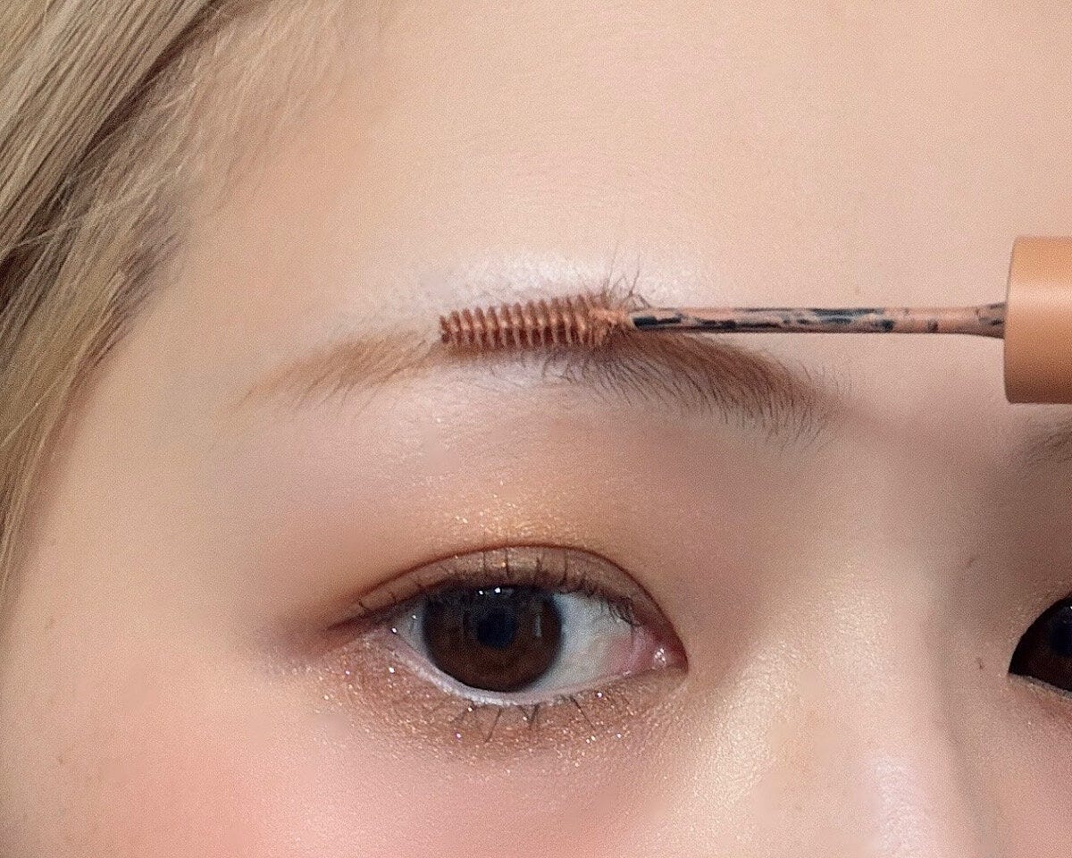 眉マスカラを眉尻から毛流れに逆らって塗る様子