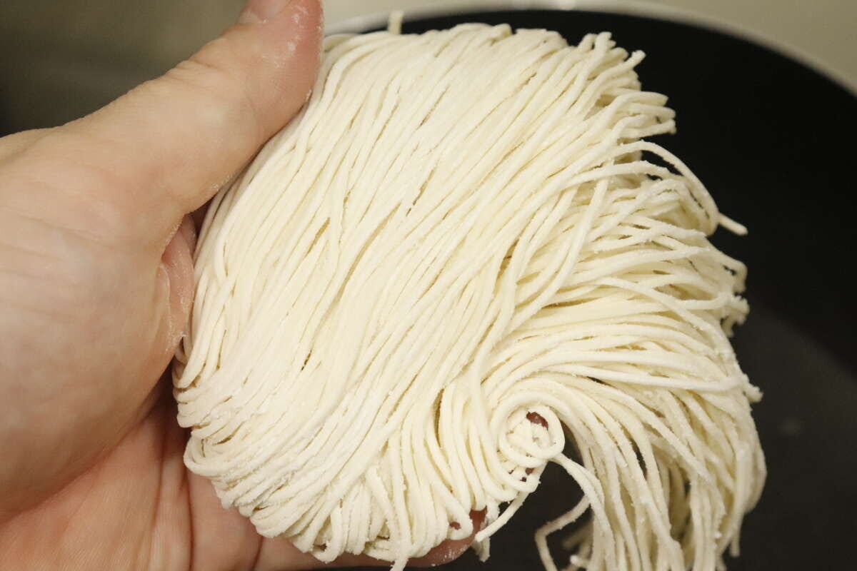 手のひらに乗せられた、白くて細い生そうめんの束 手のひらに乗せられた、白くて細い生そうめんの束