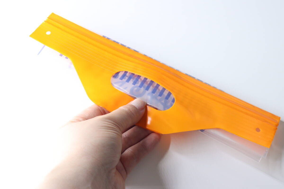 スナックバッグの持ち手部分を指で掴んでいる手元