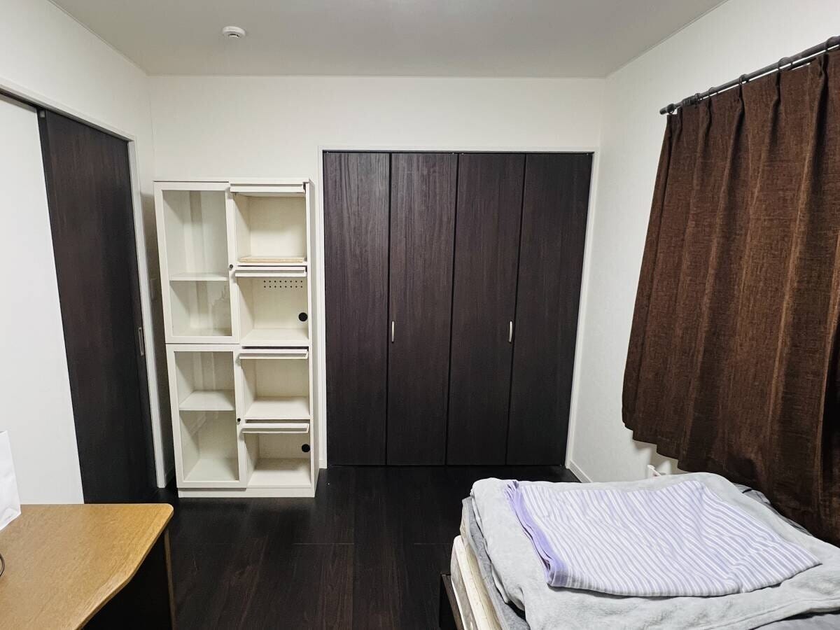 ダークブラウンの床にクローゼットと白い棚が並ぶ整頓された部屋