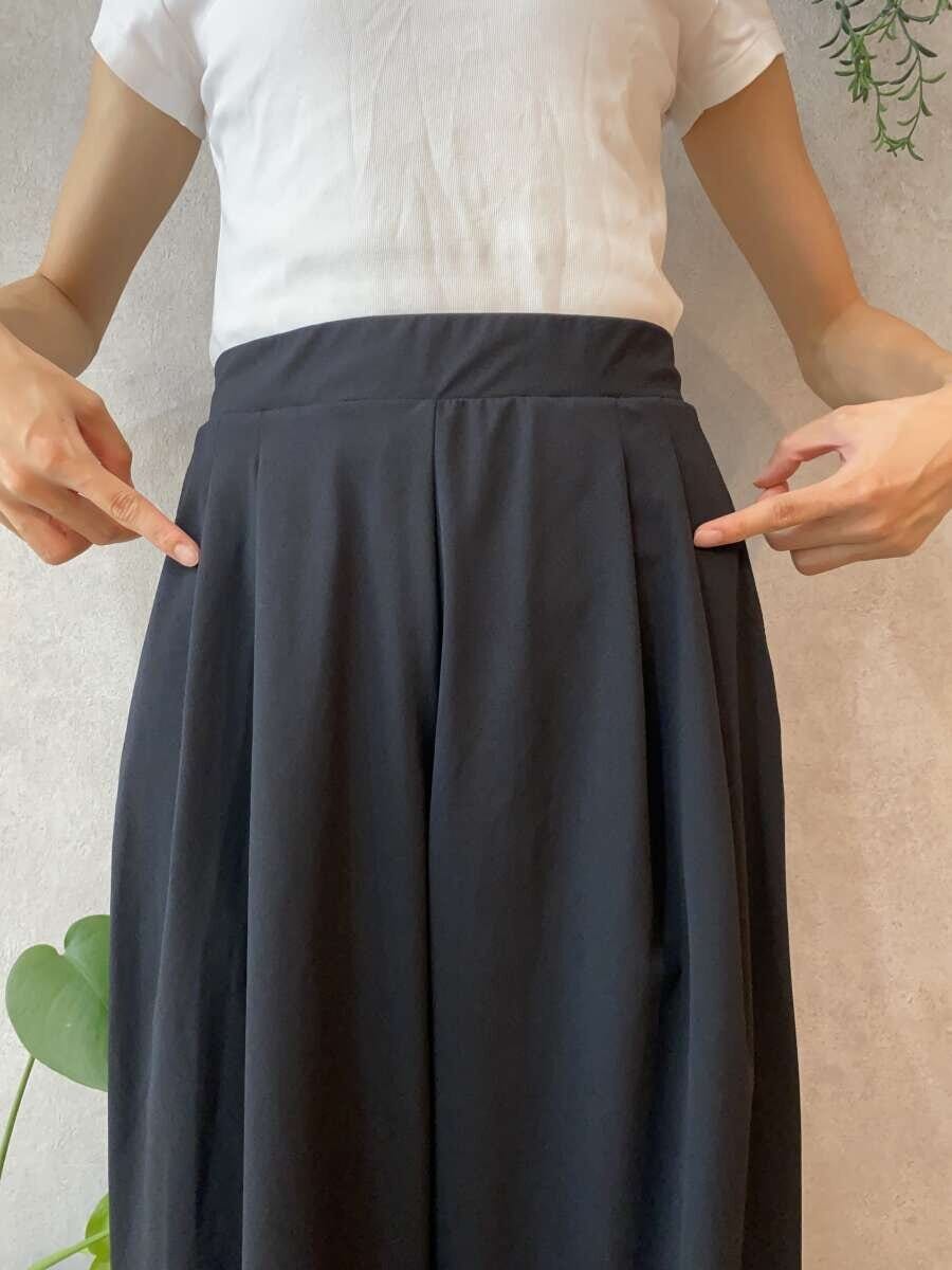 女性が黒いワイドパンツの腰部分のタックを指さしている