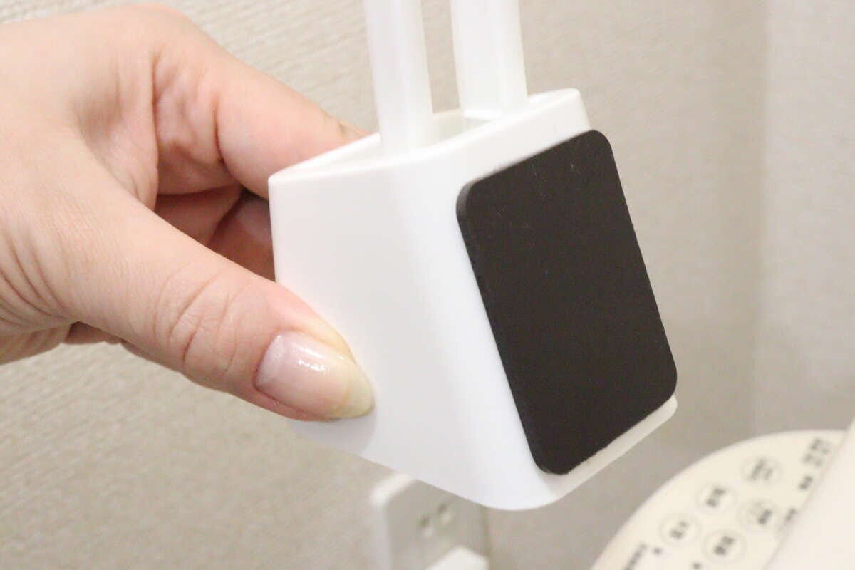 女性の指がトイレブラシのケース底面にマグネットシートを貼っている