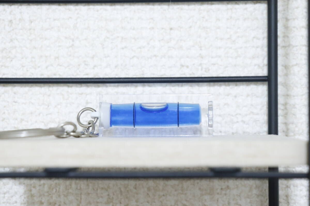白い棚の縁に置かれたキーホルダー水平器