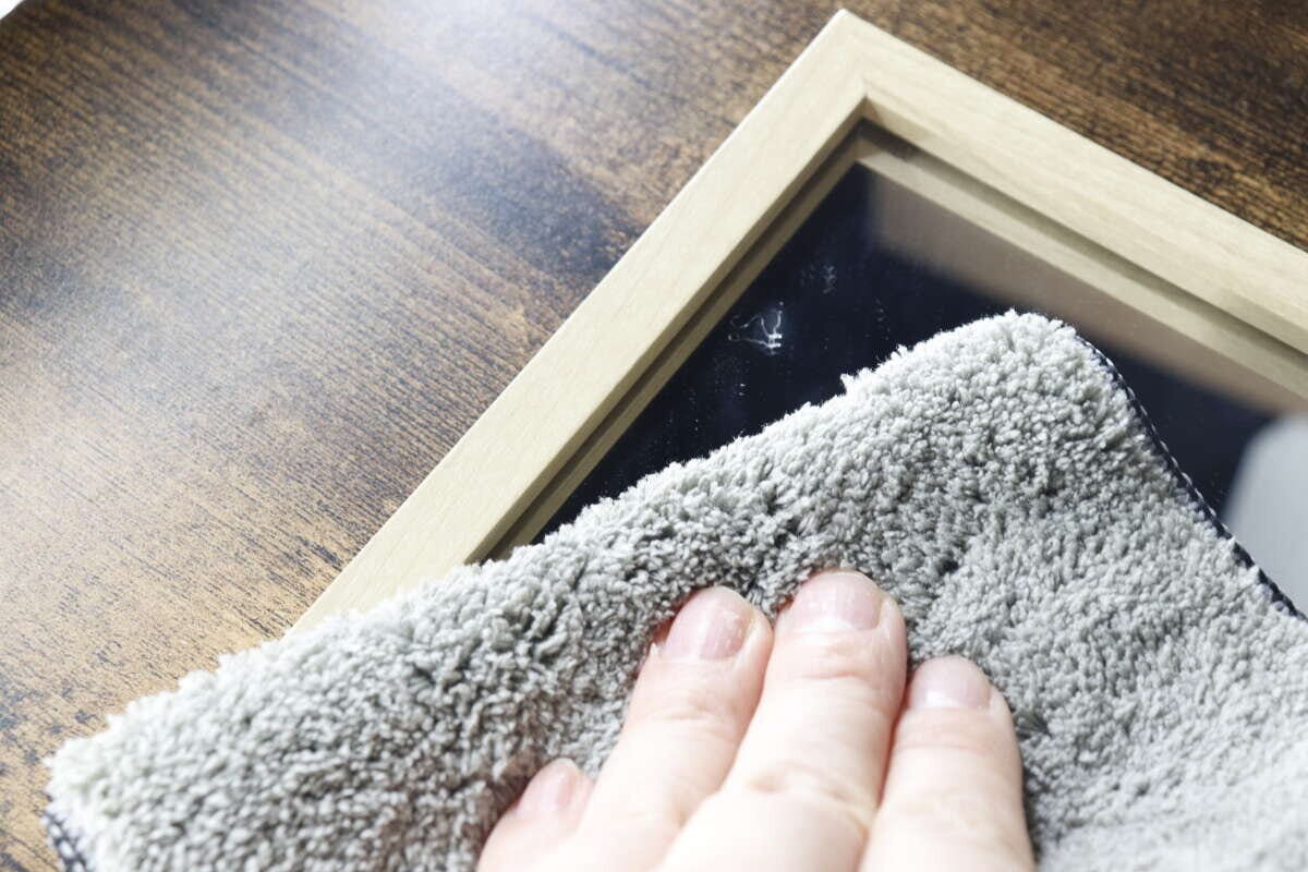 クロスのグレー面で汚れた鏡を拭いている手元 クロスのグレー面で汚れた鏡を拭いている手元