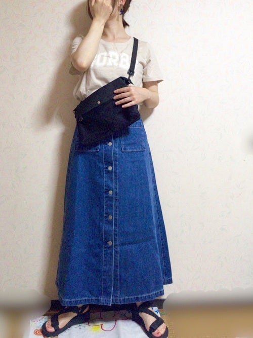 ベージュのロゴTにデニムボタンスカートを履いた女性