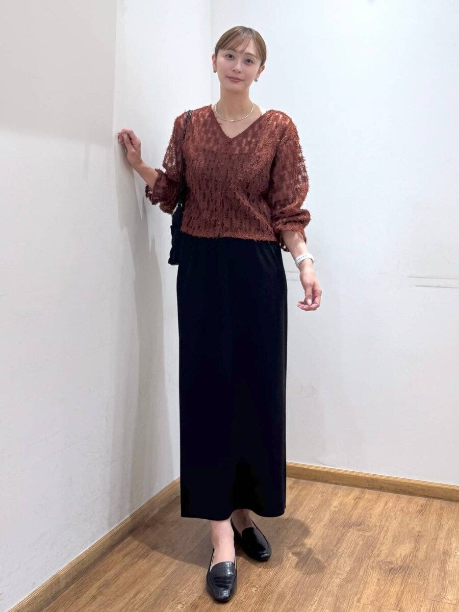 茶色のシアーフリンジトップスと黒スカートの女性 茶色のシアーフリンジトップスと黒スカートの女性