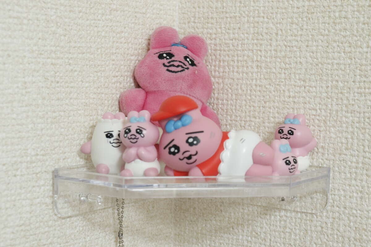 クリアコーナーラックにピンク色のマスコットやぬいぐるみが飾られている