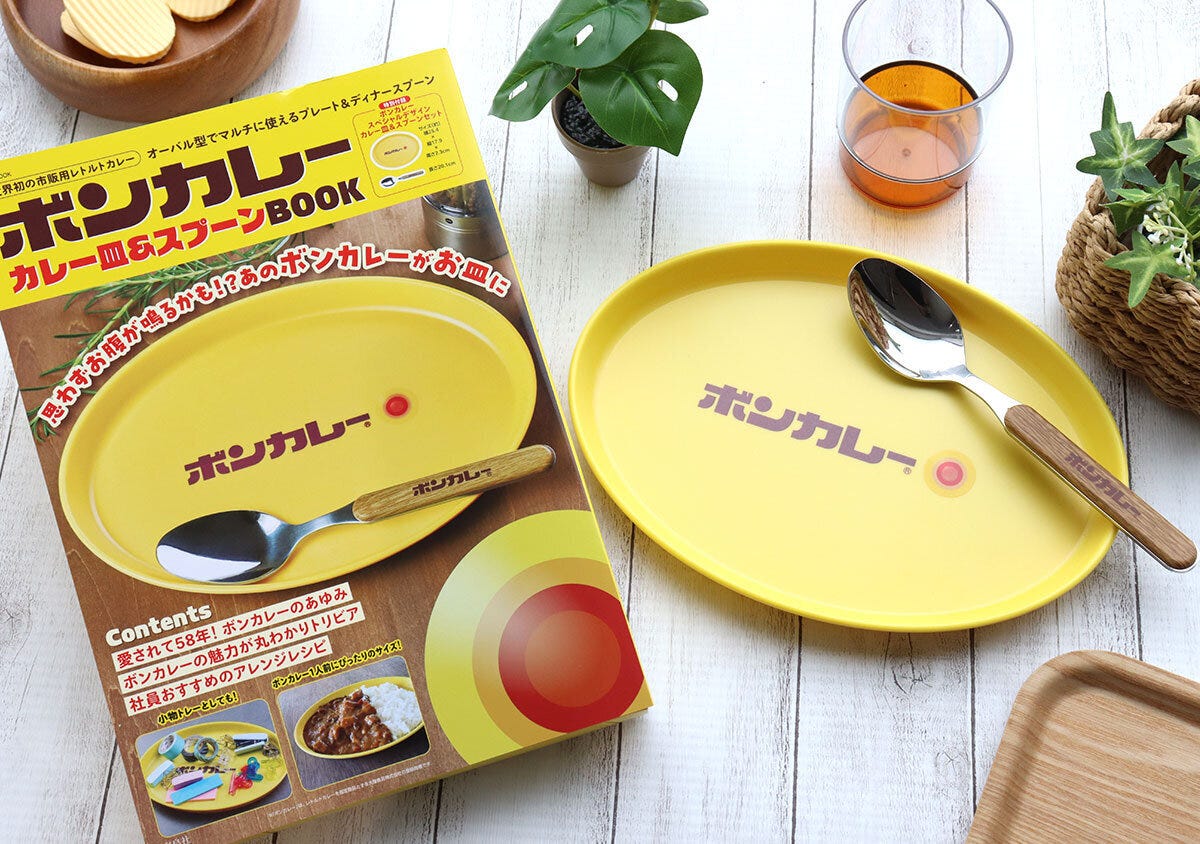 ボンカレーのムック本と、付録の黄色いカレー皿とスプーンが並べられている俯瞰写真 ボンカレーのムック本と、付録の黄色いカレー皿とスプーンが並べられている俯瞰写真