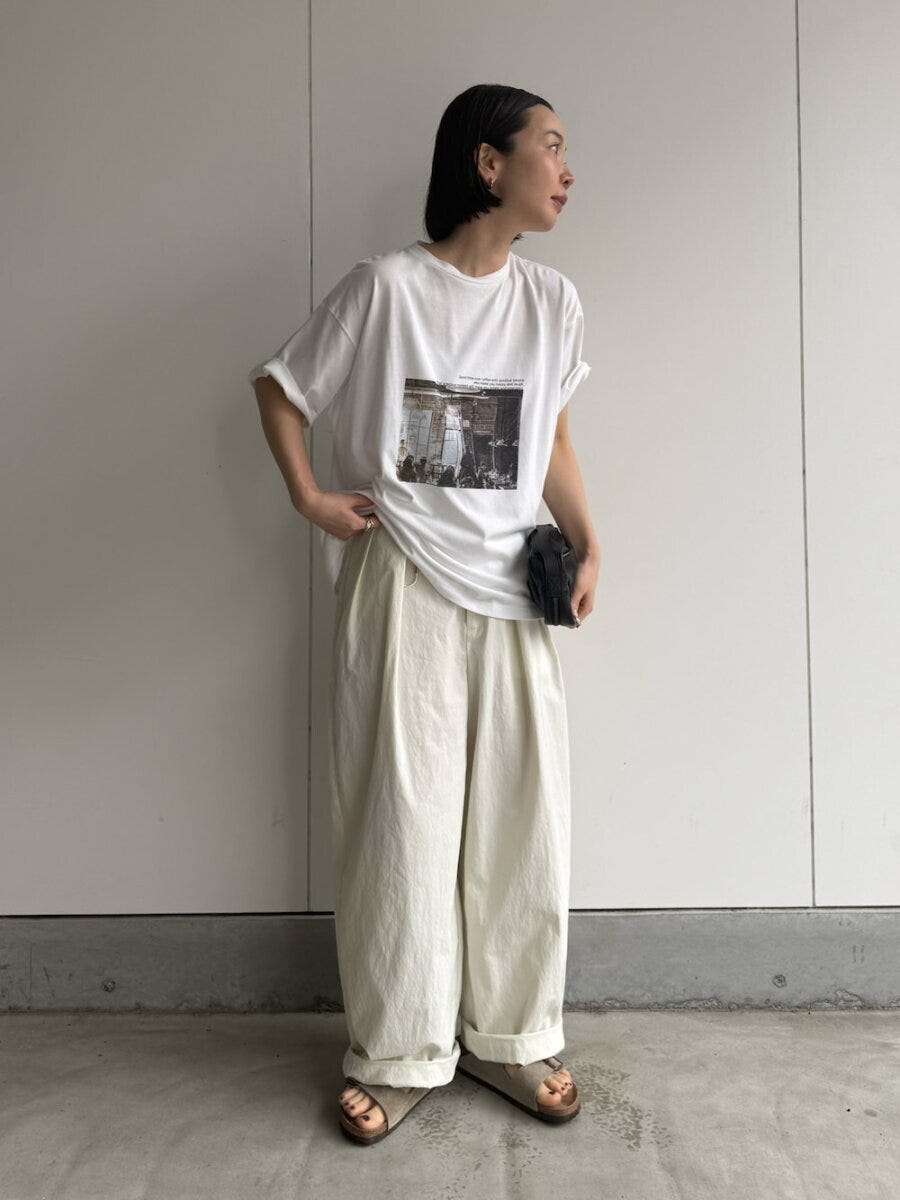 フォト白Tにオフ白ワイドパンツ、黒いミニバッグを持つ女性 フォト白Tにオフ白ワイドパンツ、黒いミニバッグを持つ女性