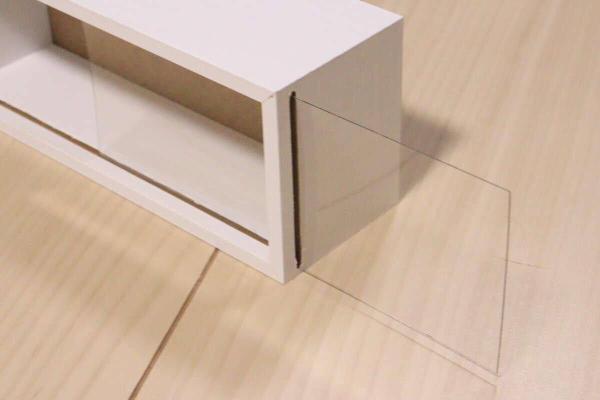 ディスプレイボックスの前面から透明な板を横にスライドさせている様子