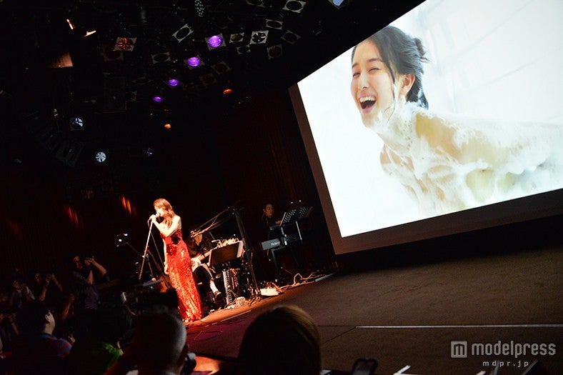 篠山氏が撮影した橋本の妖艶ショットをバックに生歌披露