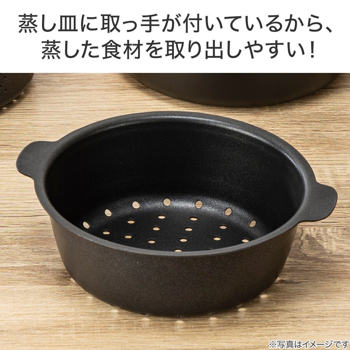 取っ手が付いた黒い蒸し皿が木製テーブルに置かれている