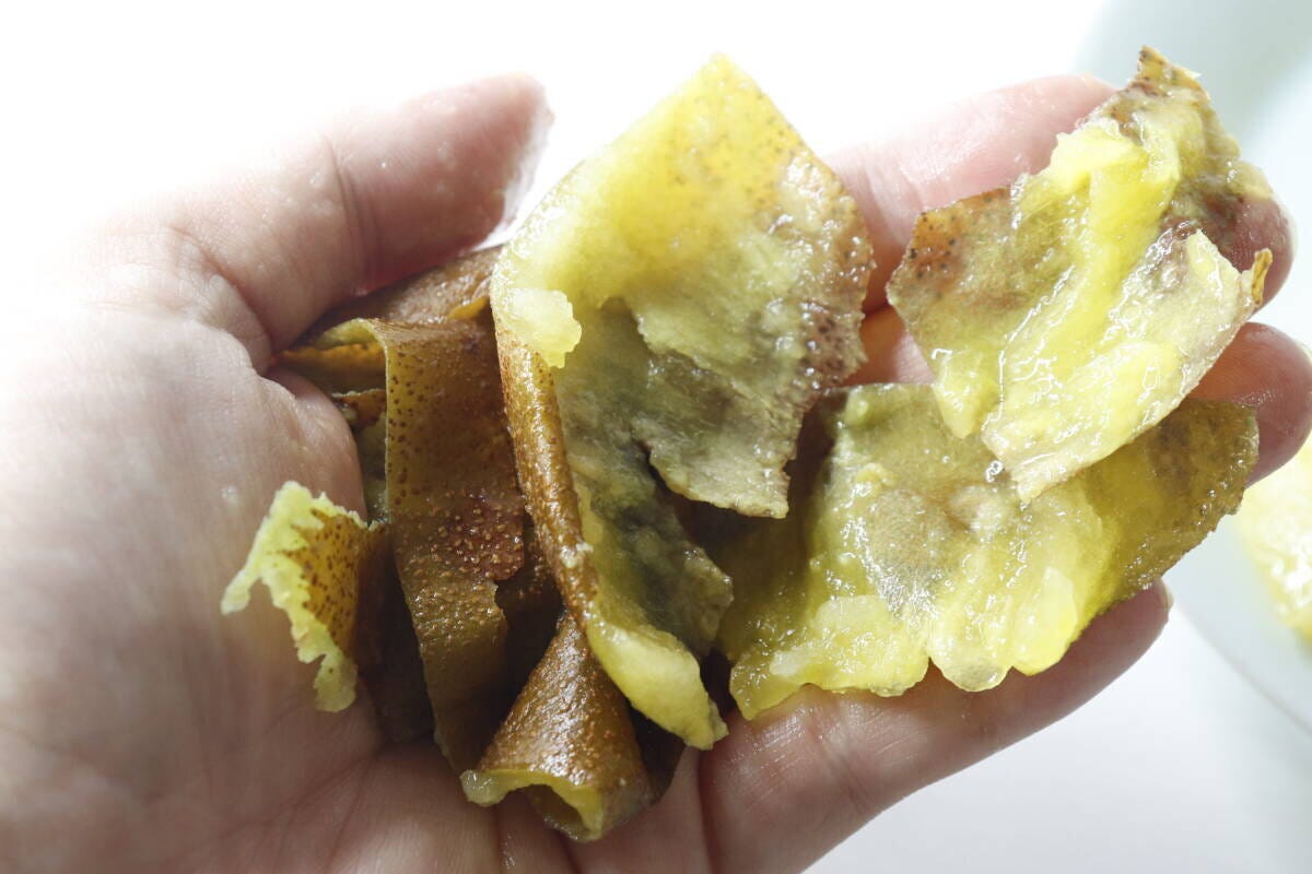 手のひらに、むき終わったキウイの皮が複数枚乗っている