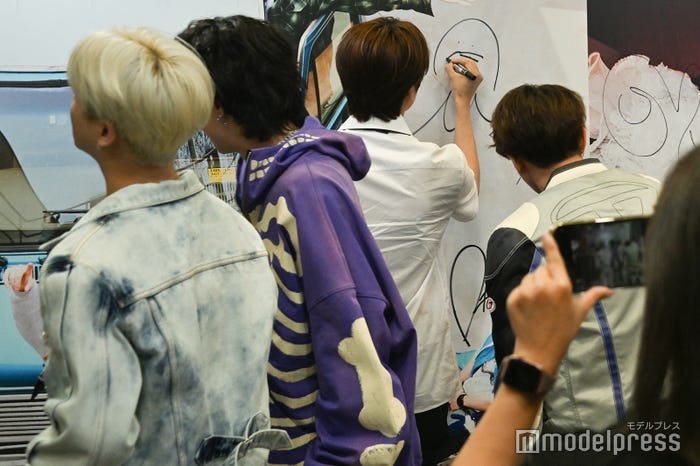 パネルにサインを記入するiKON(C)モデルプレス