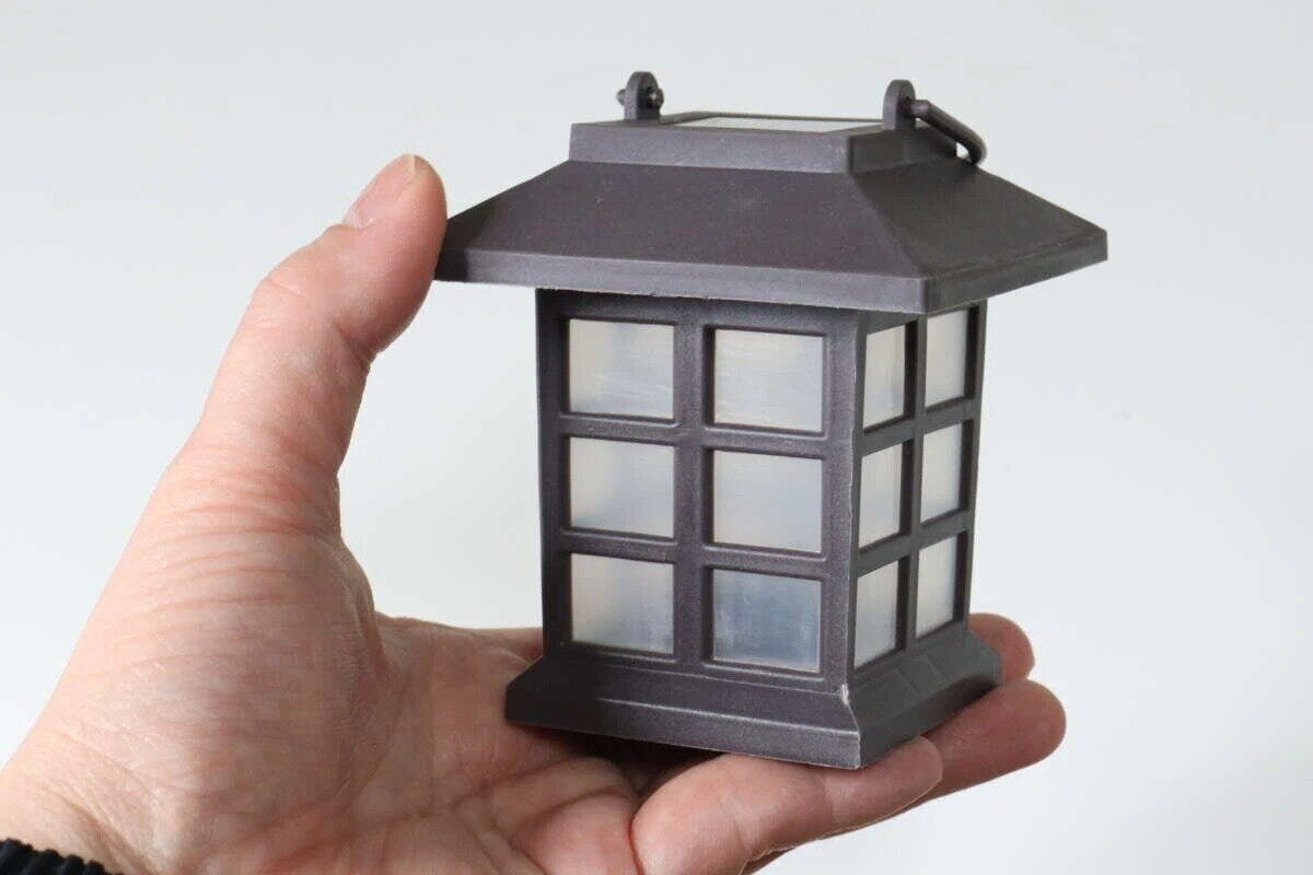 手のひらに乗せられた茶色いハウス型のソーラーライト